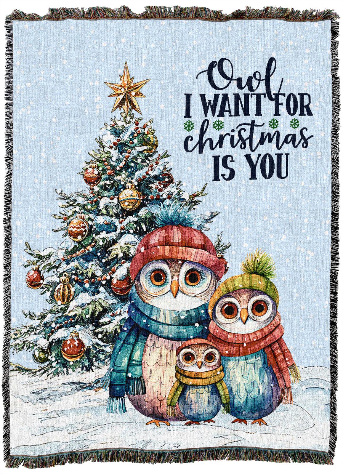 Three colorful owls in winter clothes stand in snow before a decorated Christmas tree. Text reads, Owl I want for Christmas is you. Snow is falling in the scene.