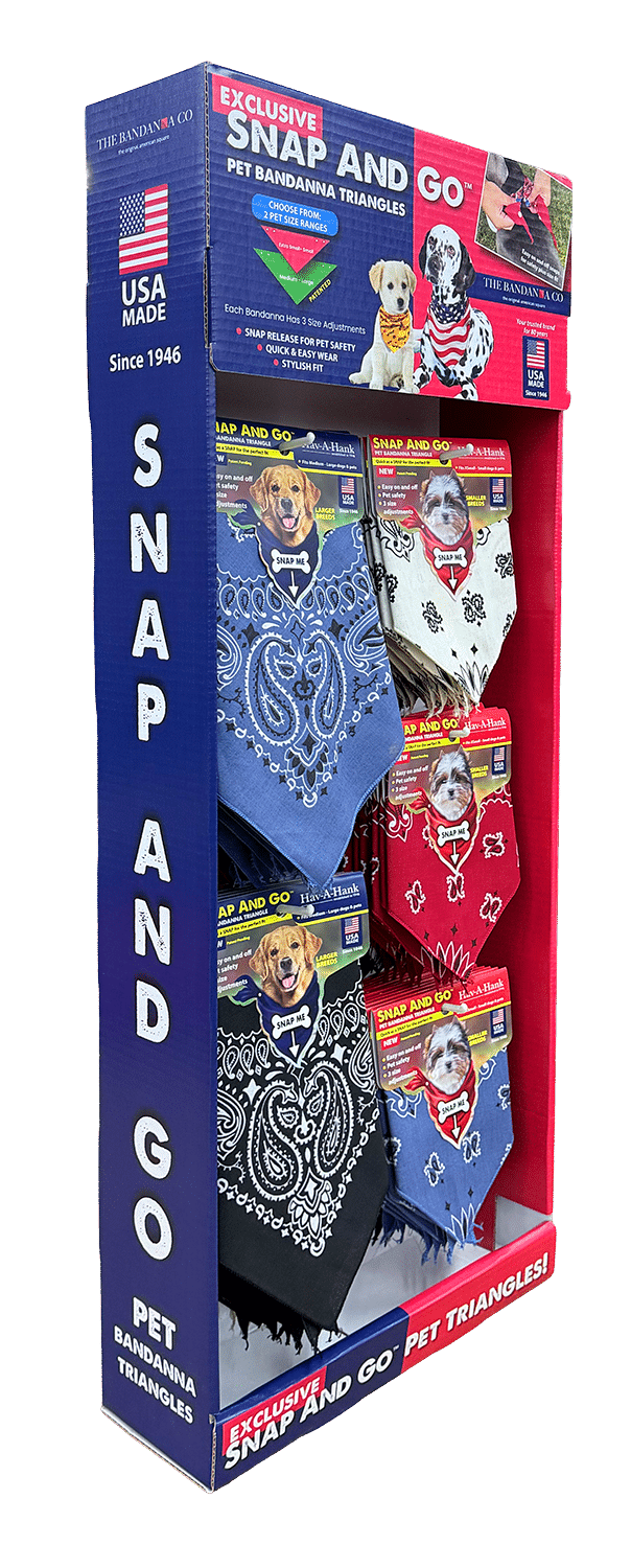 A display box with Snap and Go Pet Bandanna Triangles in blue, white, and red, each featuring a different design and a photo of a dog wearing the bandanna. The packaging highlights USA Made Since 1946..